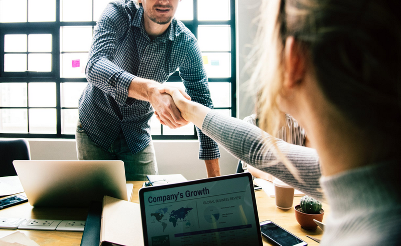 Two people shaking hands in an office setting.